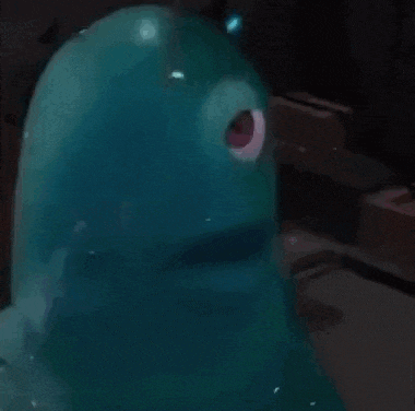 a blue cartoon character with a red eye is sitting on a table .