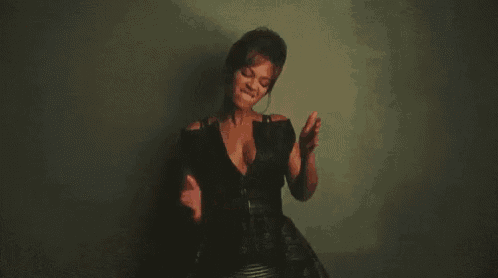 a woman in a black dress is dancing in front of a wall .