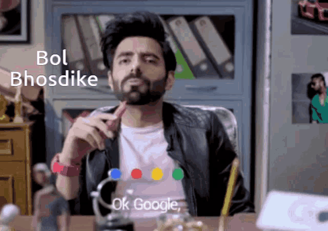 a man with a beard is sitting at a desk in front of a google logo
