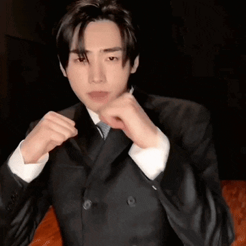 a man in a suit and tie is making a fist gesture .