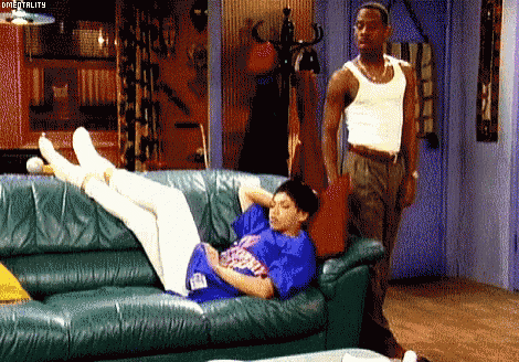 a man standing next to a woman laying on a couch
