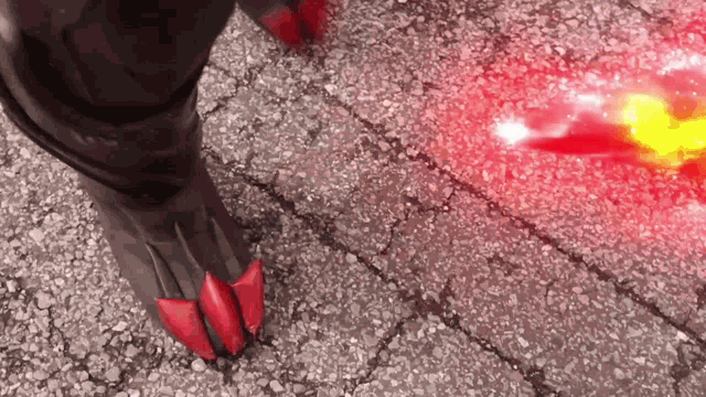 a close up of a person 's foot with red claws on a brick sidewalk