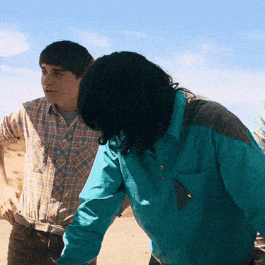a man in a plaid shirt and a woman in a blue shirt are standing next to each other