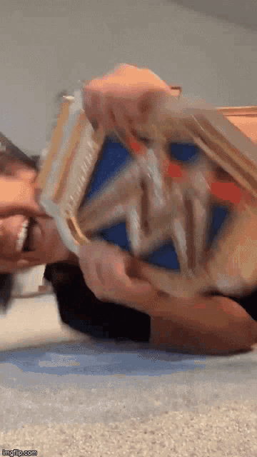 a man is laying on the floor holding a wrestling belt