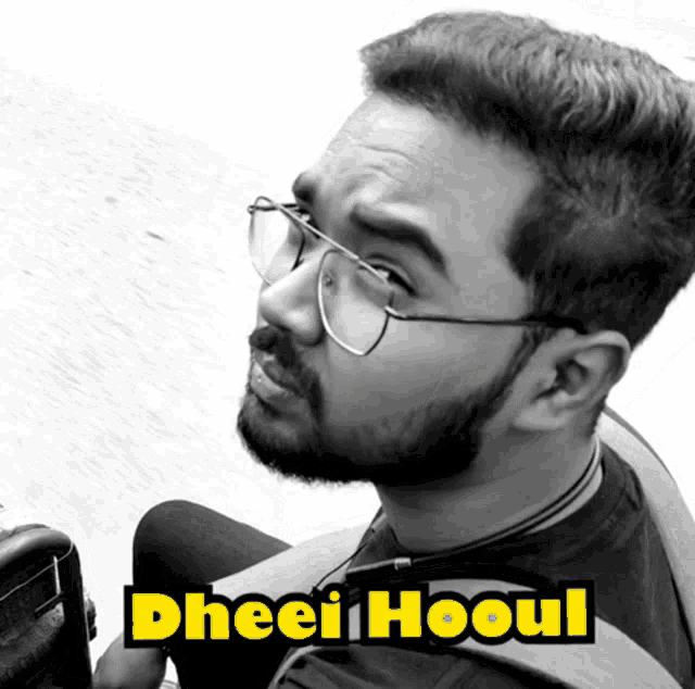 a man wearing glasses and a black shirt with the name gheei hooul written on it