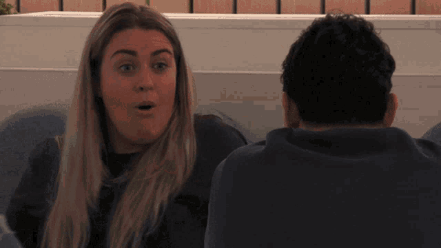 a man and a woman are sitting next to each other and the woman is looking surprised