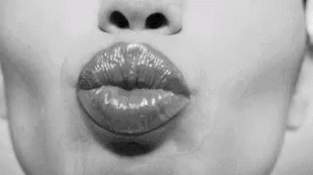 a close up of a woman 's lips blowing a kiss in black and white .