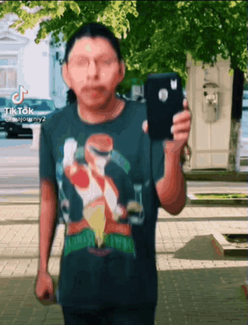 a man wearing a power rangers shirt is holding a cell phone