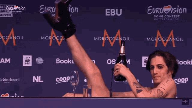 a man is holding a bottle of champagne in front of a eurovision banner