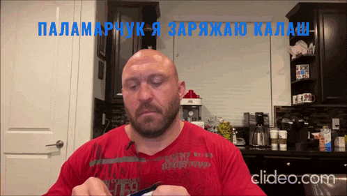 a bald man in a red shirt is sitting in a kitchen with the words " clipeo.com " below him