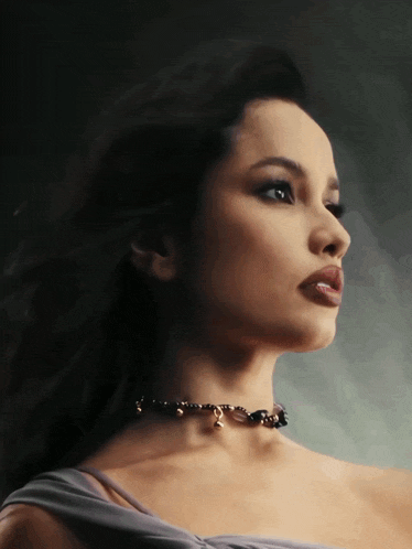 a woman with a choker around her neck looks to the left