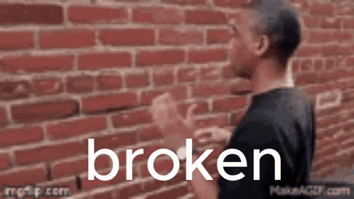 a man standing in front of a brick wall with the word broken written in white letters