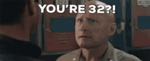 a bald man is talking to another man in a room and says `` you 're 32 '' .