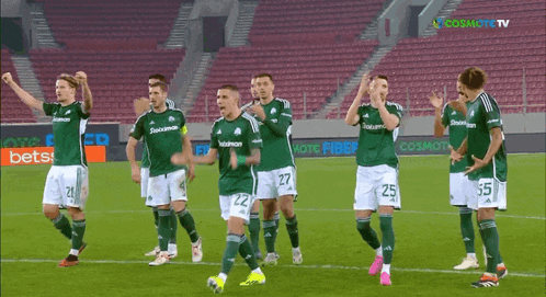 a group of soccer players are standing on a field with a cosmote tv logo in the background