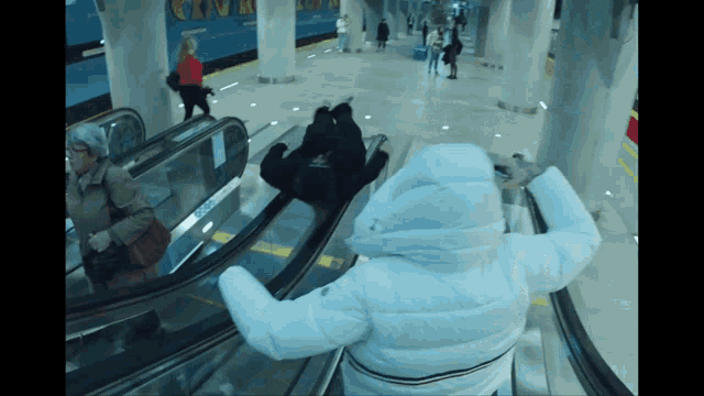 a woman in a white jacket is riding an escalator in a subway