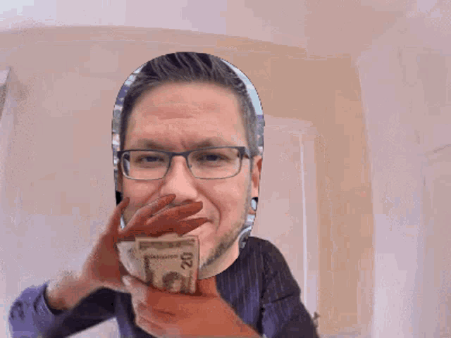 a man wearing glasses is holding a stack of money in front of his face