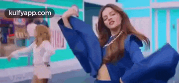 a woman in a blue dress is dancing in a video .
