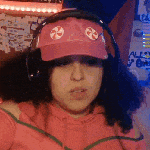 a woman wearing headphones and a pink hat has a candy cane on her hat
