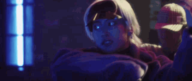 a man in a hat is standing next to a woman in a dark room .