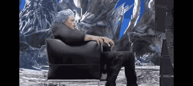 a man with gray hair is sitting in a chair in front of a mountain .