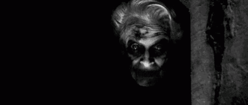 a black and white photo of a scary clown with smoke coming out of its mouth .