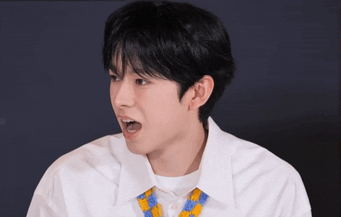 a young man with a surprised look on his face is wearing a white shirt