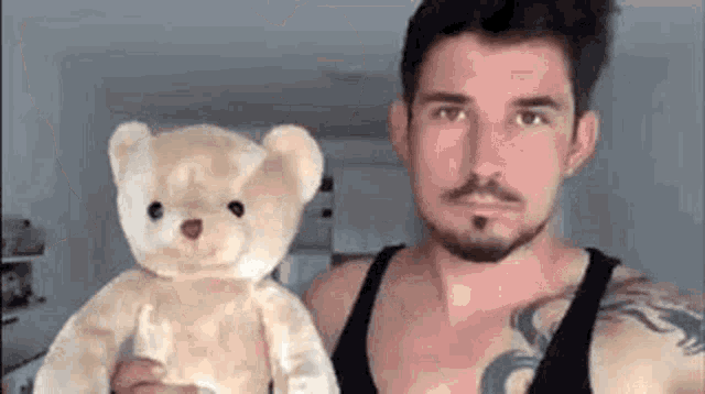 a man with a beard is holding a teddy bear in his hands .