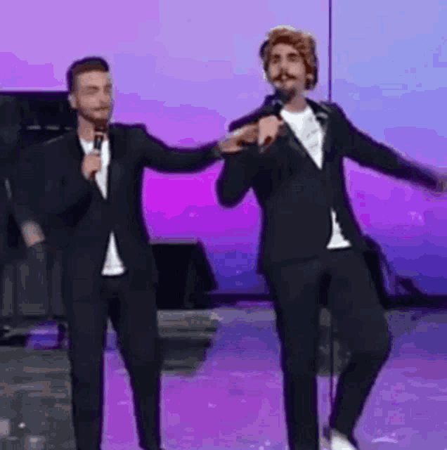 two men in suits are standing next to each other on a stage .