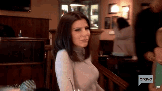 a woman sitting at a table with bravo written on the bottom of the screen