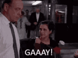 a man and a woman are standing next to each other in a room and the woman is holding a rose .