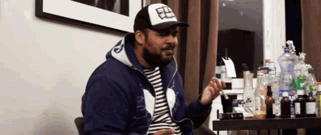 a man with a beard wearing a blue jacket and a hat with the letter e on it