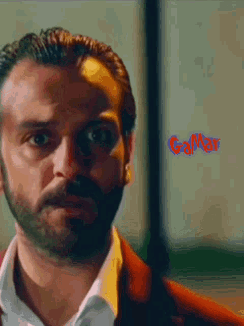 a man with a beard is looking at the camera and the word gamer is visible in red