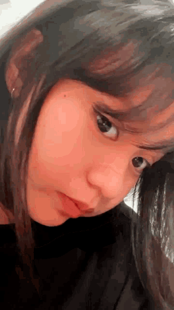 a close up of a girl 's face with a black shirt on looking at the camera .
