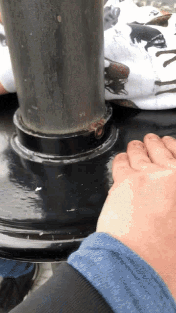 a person 's hand rests on a metal pipe