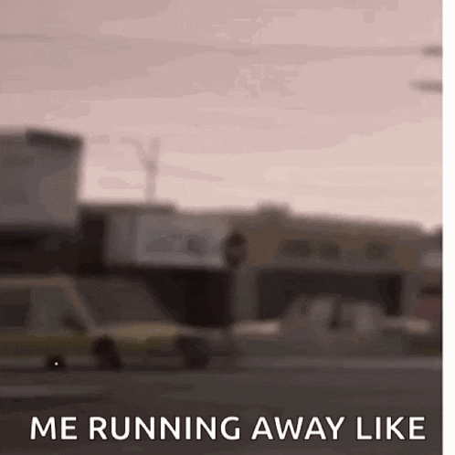 a blurry picture of a city street with a car driving down it and the words `` me running away like '' .