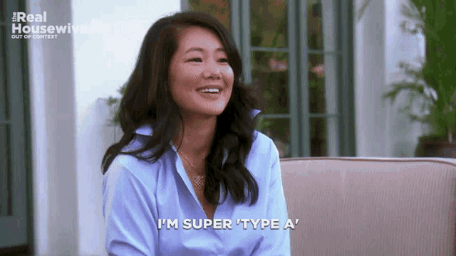 a woman is sitting on a couch and smiling and says i 'm super type a '
