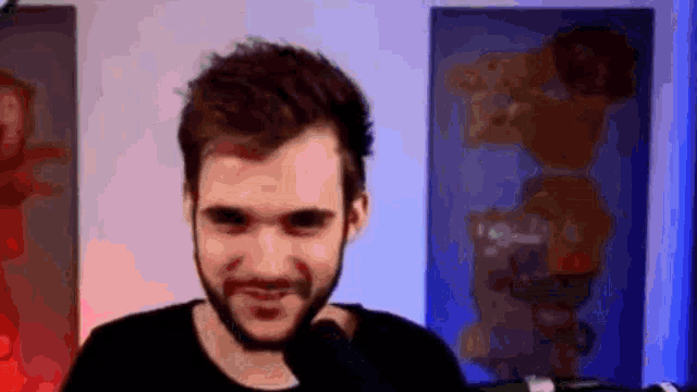 a man with a beard is making a funny face in front of a microphone in a room .