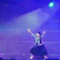 a person is jumping in the air on a stage with a microphone in their hand
