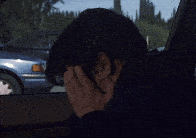a man sitting in a car covering his face with his hand