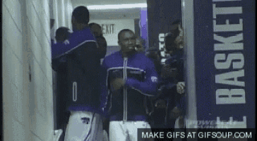 a group of basketball players standing in a hallway with a sign that says basket