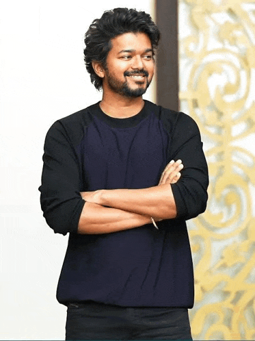a man with a beard and mustache is standing with his arms crossed and smiling .