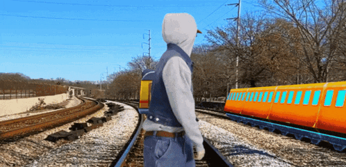 a man standing on train tracks looking at a train