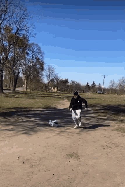 a man in a black jacket and white shorts is running in a park