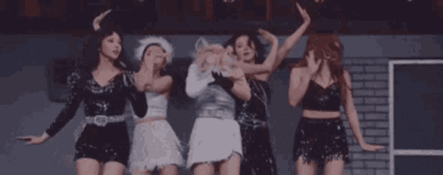 a group of women are standing next to each other dancing in a room .