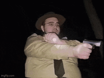 a man in a hat and tie is pointing a gun at the camera ..