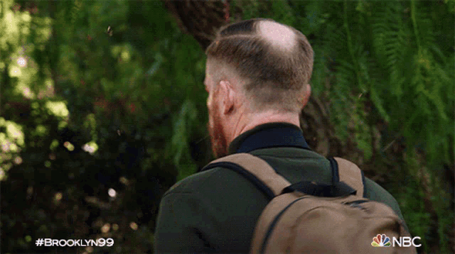 a man with a backpack is talking to another man with a brooklyn99 logo on the bottom
