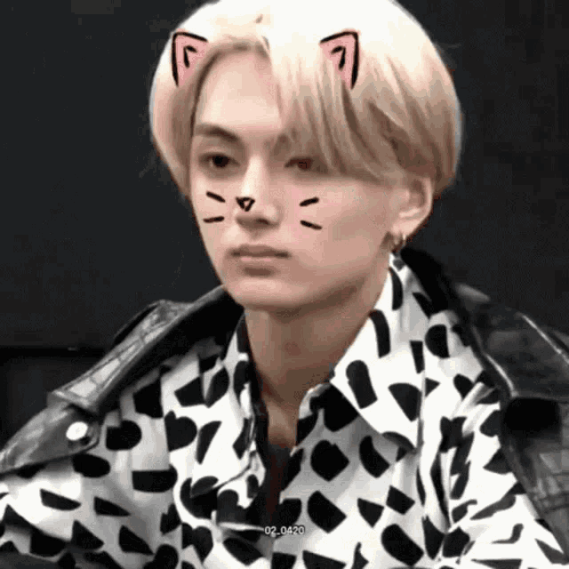 a young man wearing a black and white shirt with cat ears on his face .