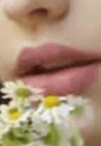 a close up of a woman 's lips with a flower in the foreground