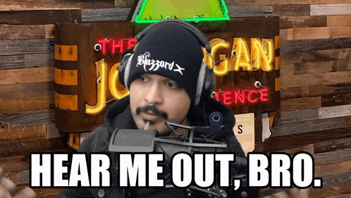 a man wearing headphones stands in front of a sign that says hear me out bro