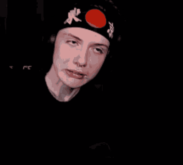 a man wearing a black headband with a red circle on it .
